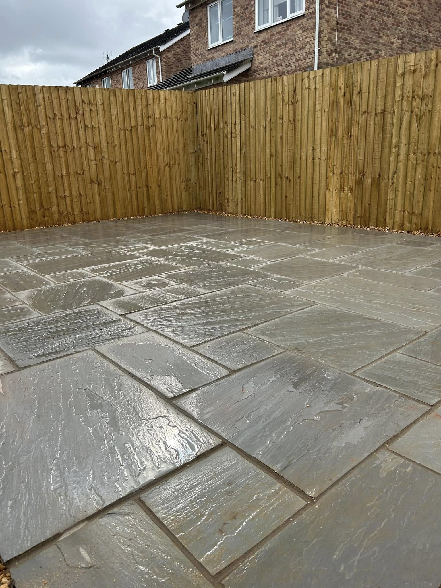 Indian sandstone patio with vertical closeboard timber fencing, freshly laid in a South Wales back garden